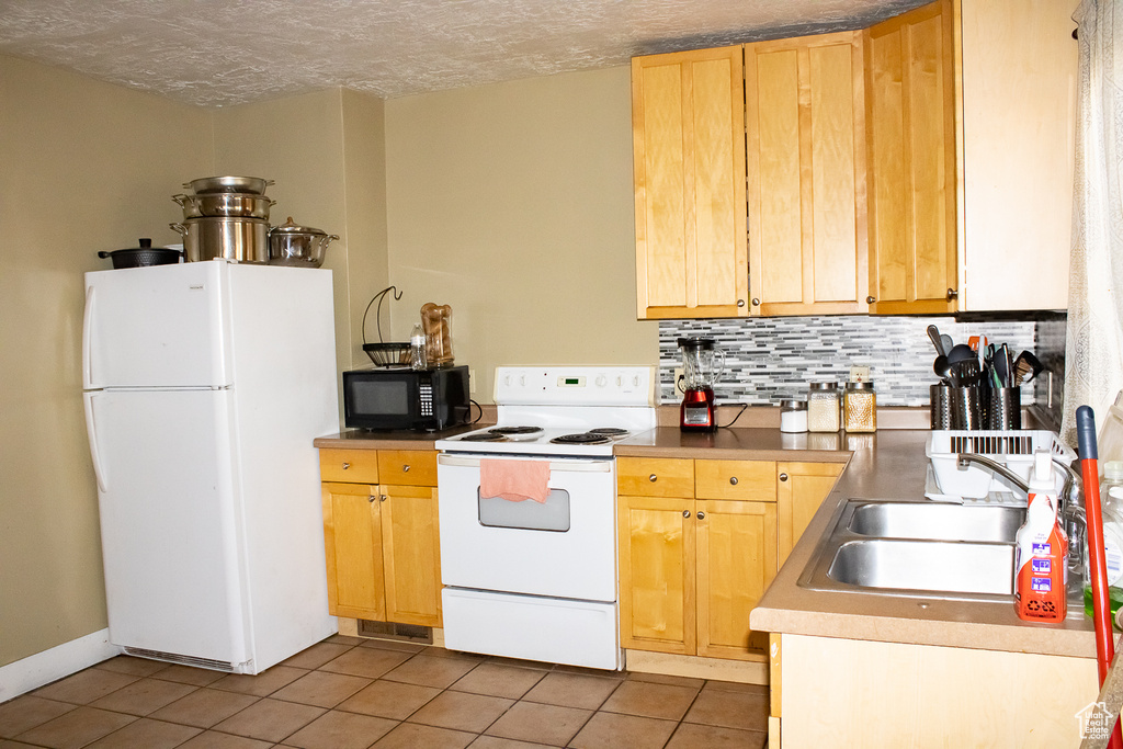 Kitchen featuring tile patterned flooring, tasteful backsplash, light brown cabinets, white appliances, and sink