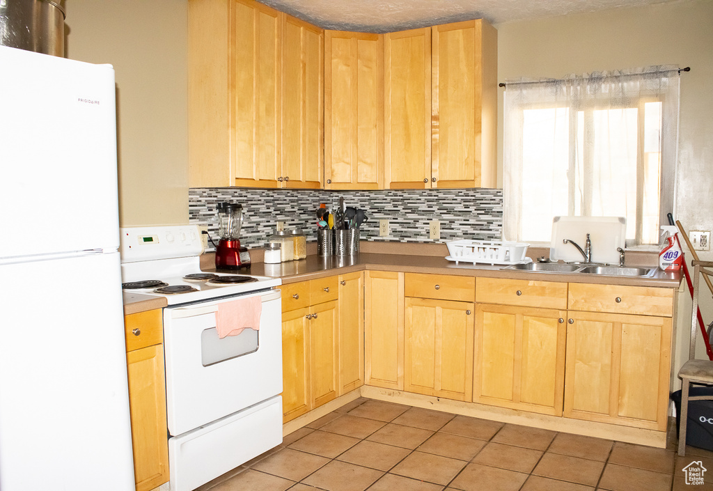 Kitchen with white appliances, sink, light tile patterned floors, decorative backsplash, and light brown cabinetry