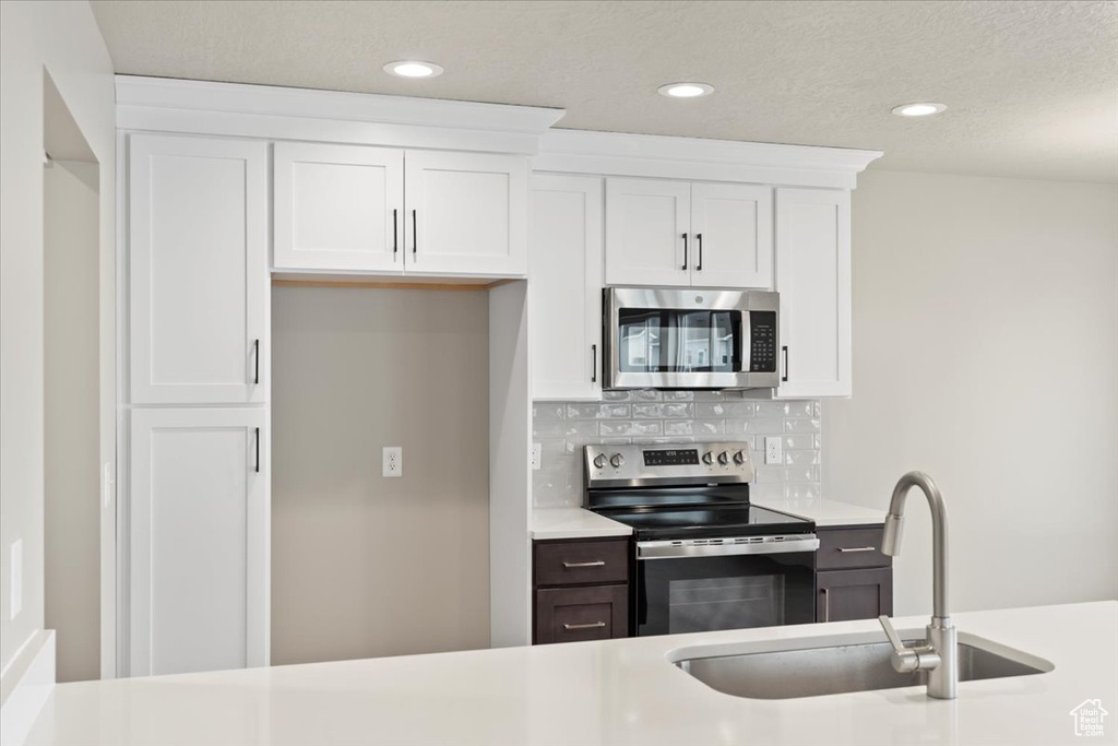 Kitchen with stainless steel appliances, sink, and white cabinets