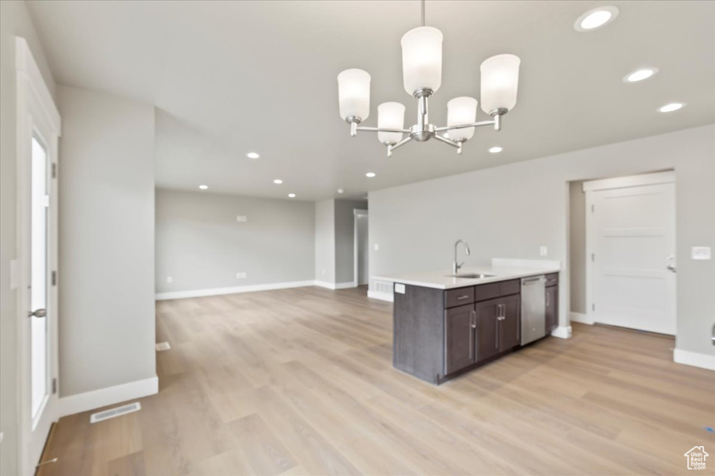 Kitchen with dishwasher, sink, hanging light fixtures, dark brown cabinets, and light wood-type flooring