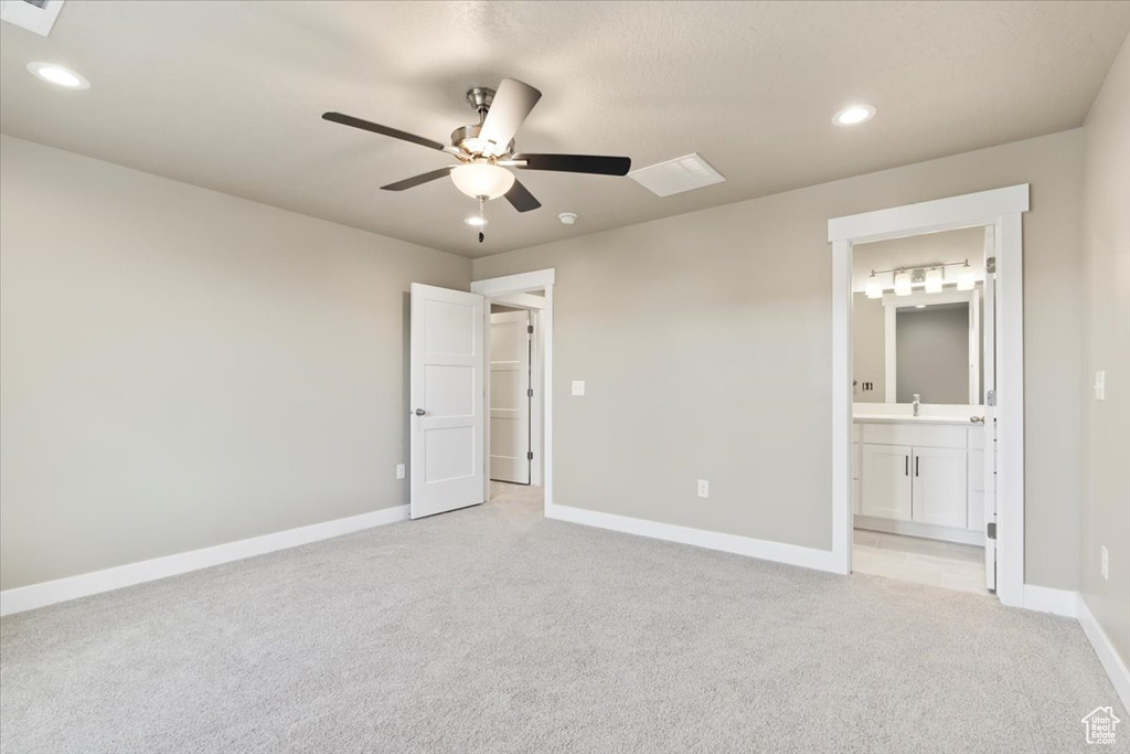 Unfurnished bedroom with sink, light colored carpet, ceiling fan, and ensuite bathroom