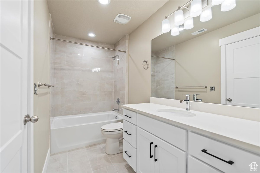 Full bathroom featuring vanity, toilet, tiled shower / bath combo, and tile patterned flooring
