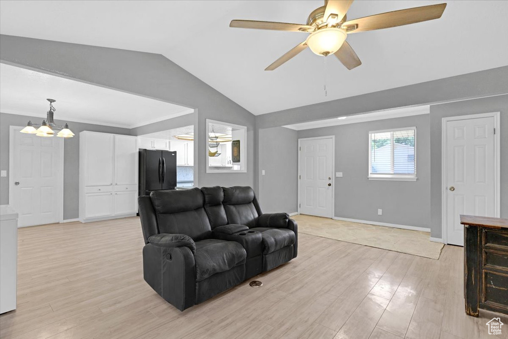 Living room featuring ceiling fan with notable chandelier, lofted ceiling, and light wood-type flooring