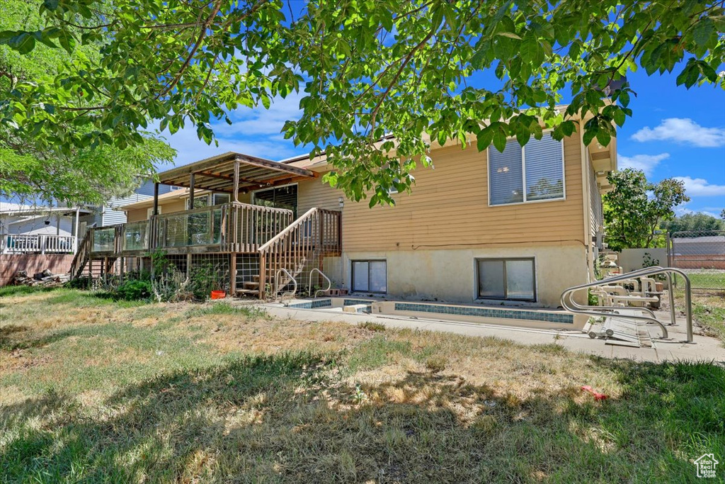 Back of house featuring a wooden deck and a yard