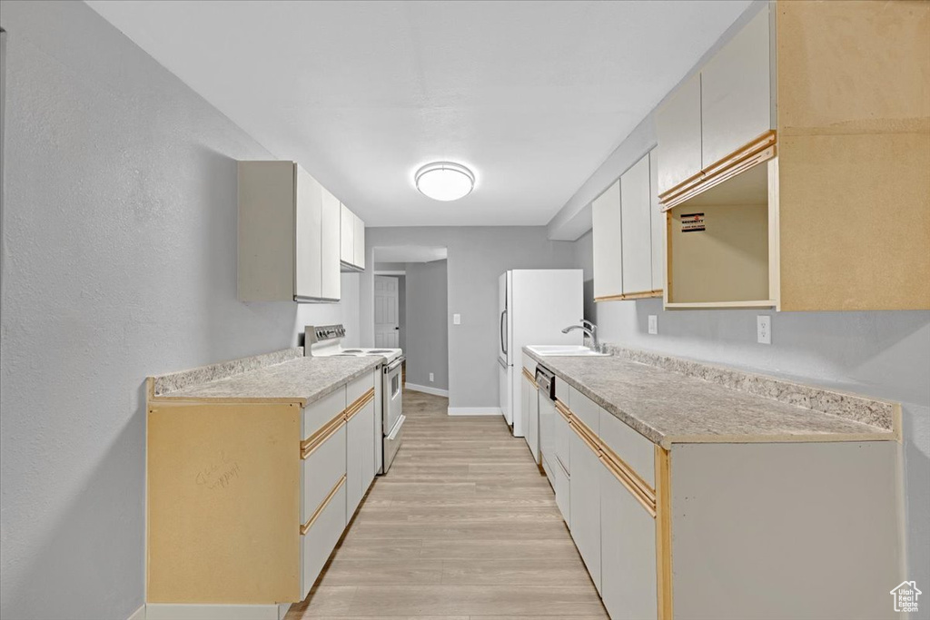 Kitchen featuring light wood-type flooring, sink, and white electric range oven