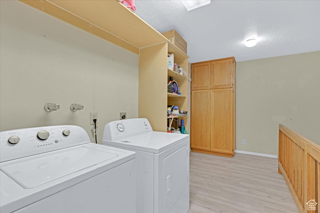 Laundry room featuring washing machine and clothes dryer, a textured ceiling, and light hardwood / wood-style floors