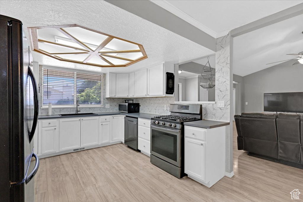 Kitchen with decorative backsplash, stainless steel appliances, light hardwood / wood-style flooring, and ceiling fan