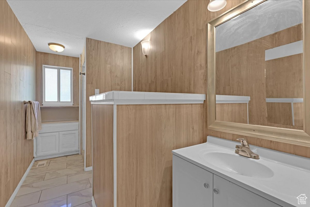 Bathroom featuring wood walls, vanity, and tile patterned flooring