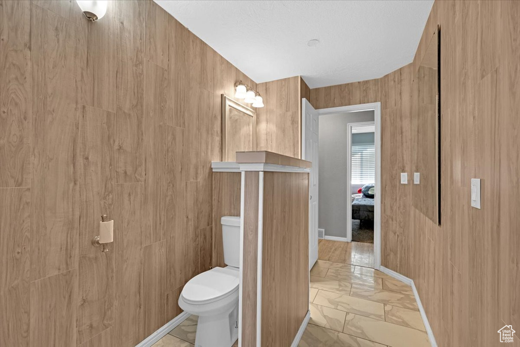 Bathroom featuring wooden walls, tile patterned floors, and toilet