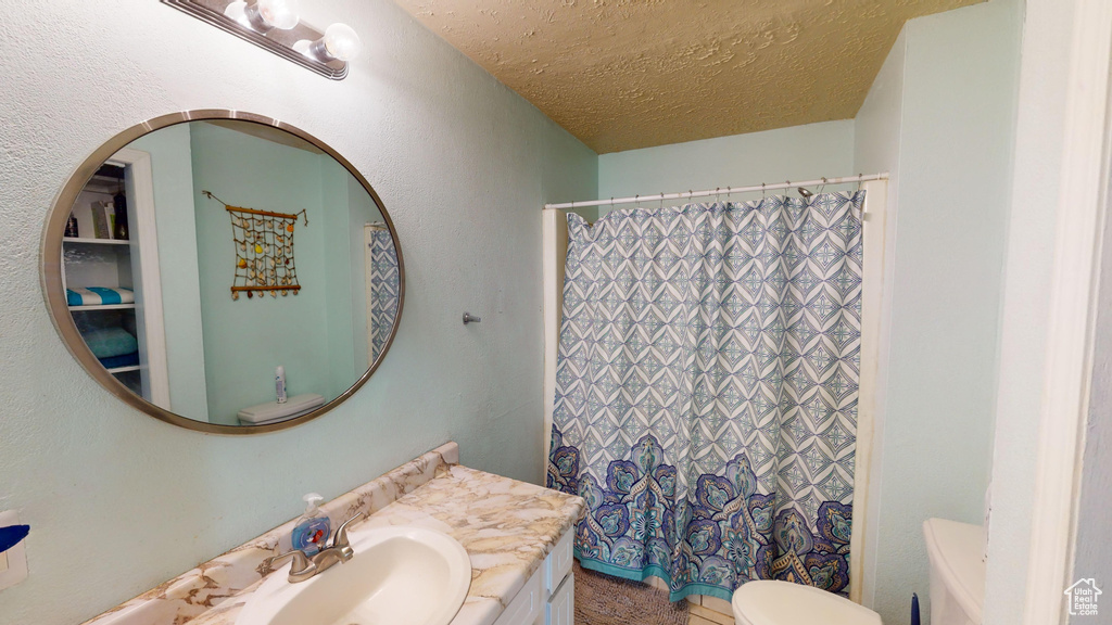 Bathroom with vanity, a textured ceiling, and toilet