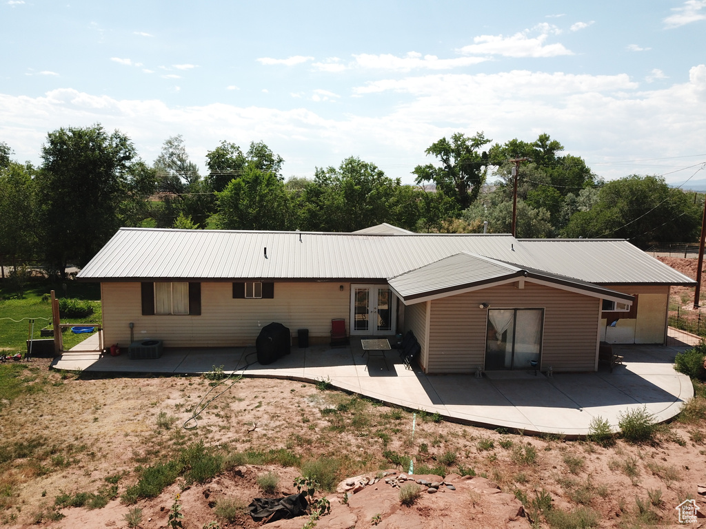 Back of property with cooling unit and a patio