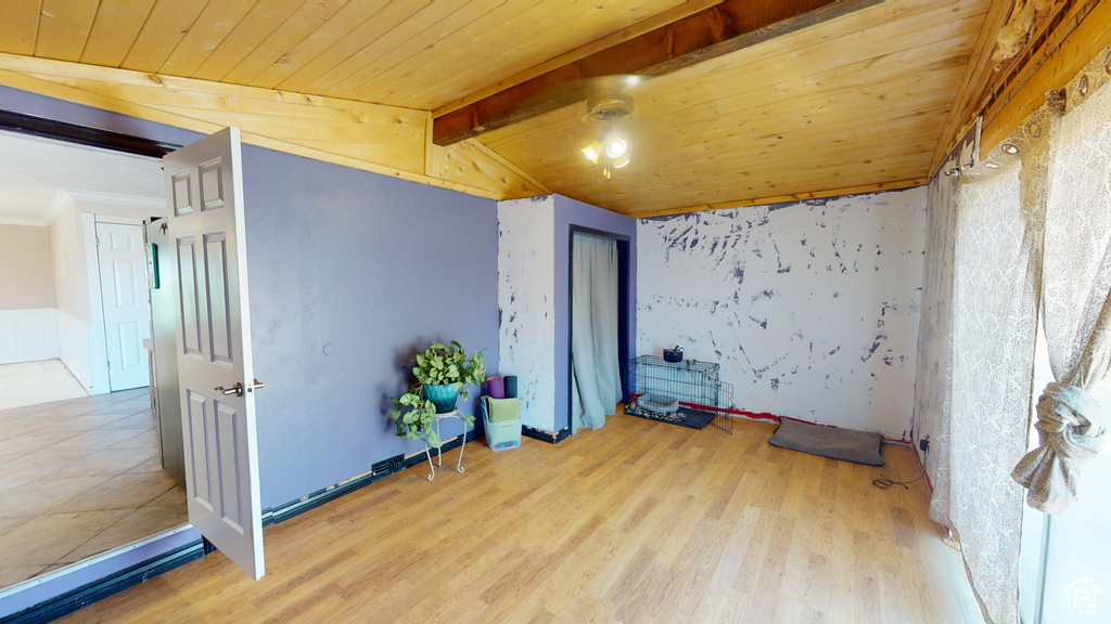 Empty room featuring wood ceiling, beamed ceiling, and light hardwood / wood-style flooring