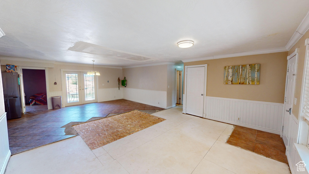 Tiled entrance foyer featuring crown molding and french doors