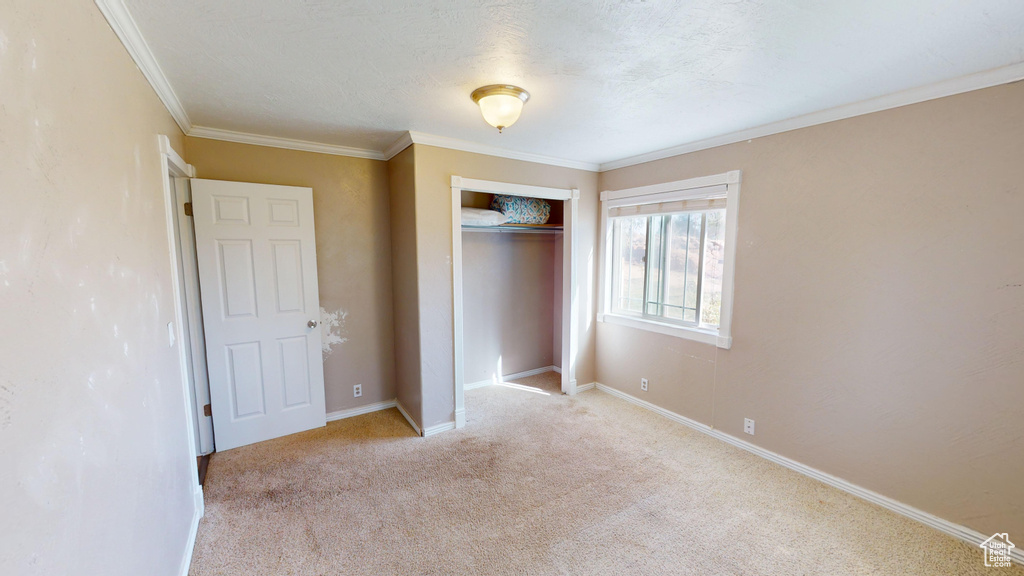 Unfurnished bedroom featuring ornamental molding, a closet, and light carpet