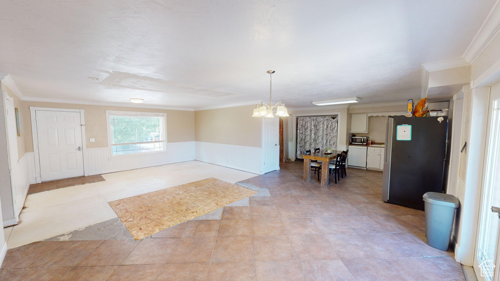 Kitchen with decorative light fixtures, ornamental molding, an inviting chandelier, appliances with stainless steel finishes, and light tile patterned floors