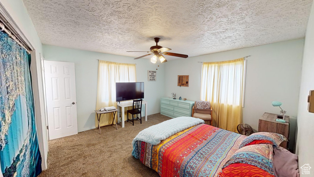 Carpeted bedroom with a textured ceiling and ceiling fan