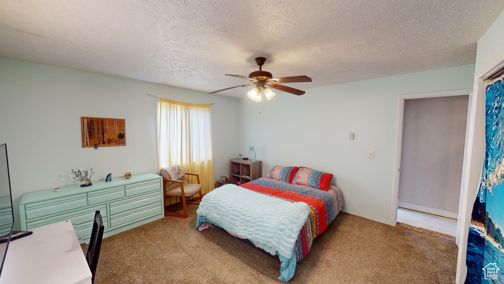 Bedroom featuring a textured ceiling, carpet floors, and ceiling fan