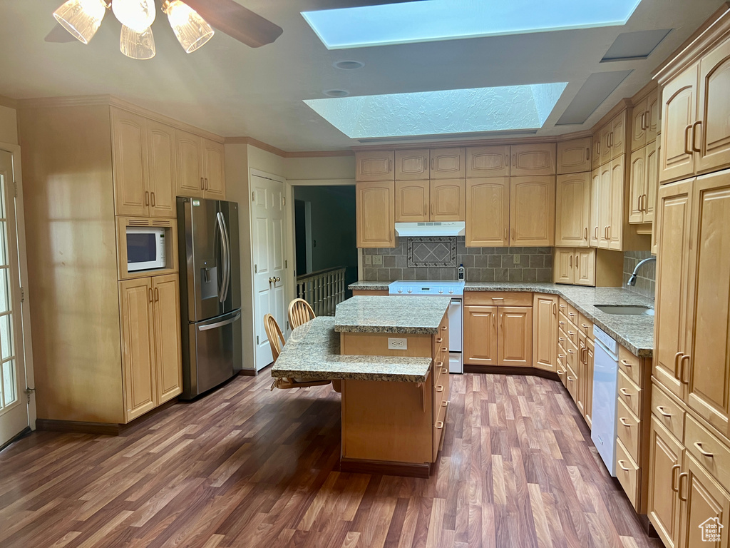 Kitchen featuring white appliances, dark hardwood / wood-style floors, a skylight, a center island, and ceiling fan