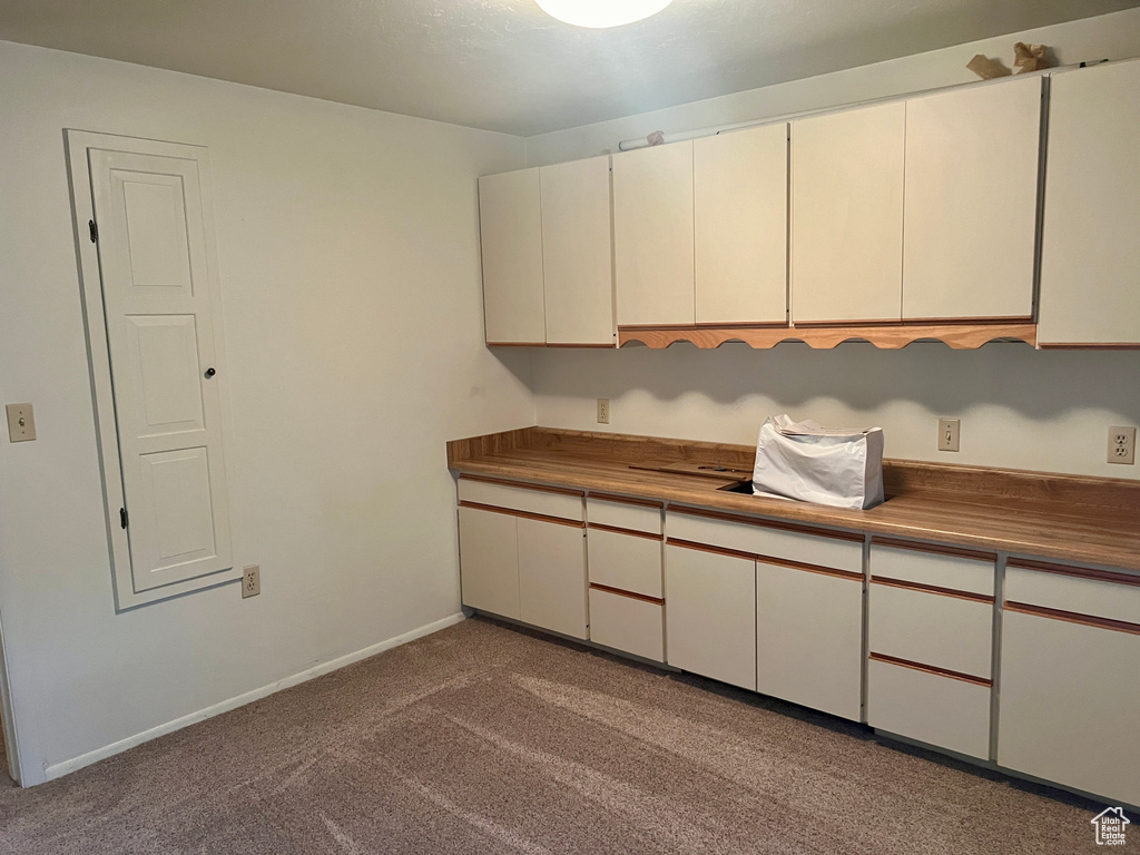 Kitchen featuring white cabinets and carpet