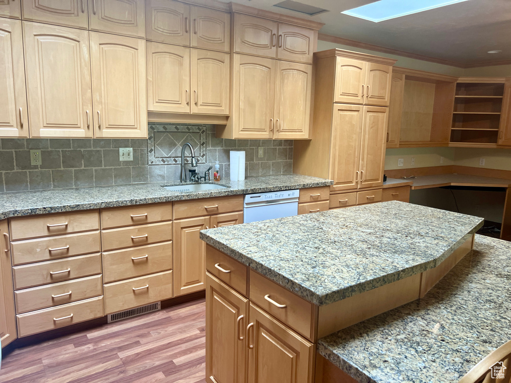 Kitchen featuring light hardwood / wood-style flooring, dishwasher, a kitchen island, decorative backsplash, and sink