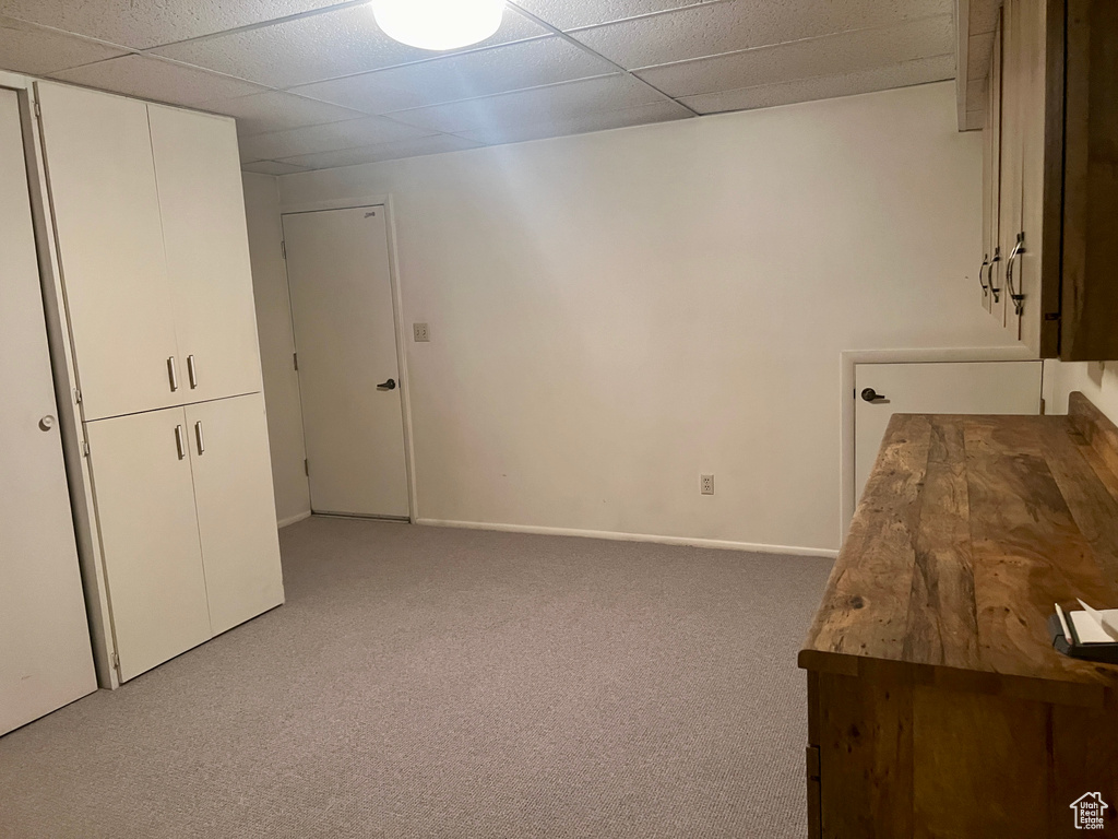 Unfurnished bedroom featuring light carpet and a drop ceiling