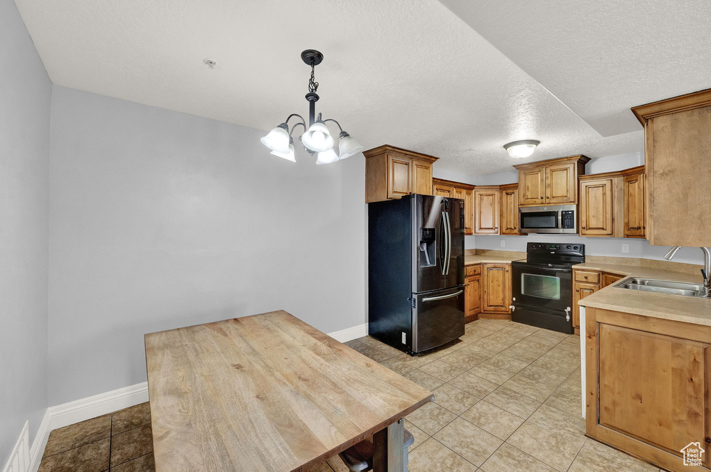 Kitchen with black appliances, sink, hanging light fixtures, light tile patterned flooring, and a chandelier