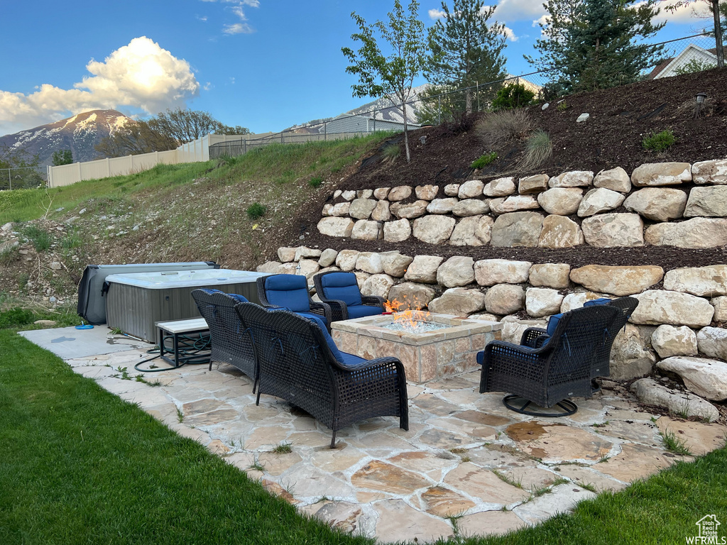 View of patio featuring a mountain view, a hot tub, and a fire pit