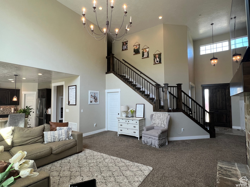 Living room featuring dark colored carpet, a chandelier, and a high ceiling