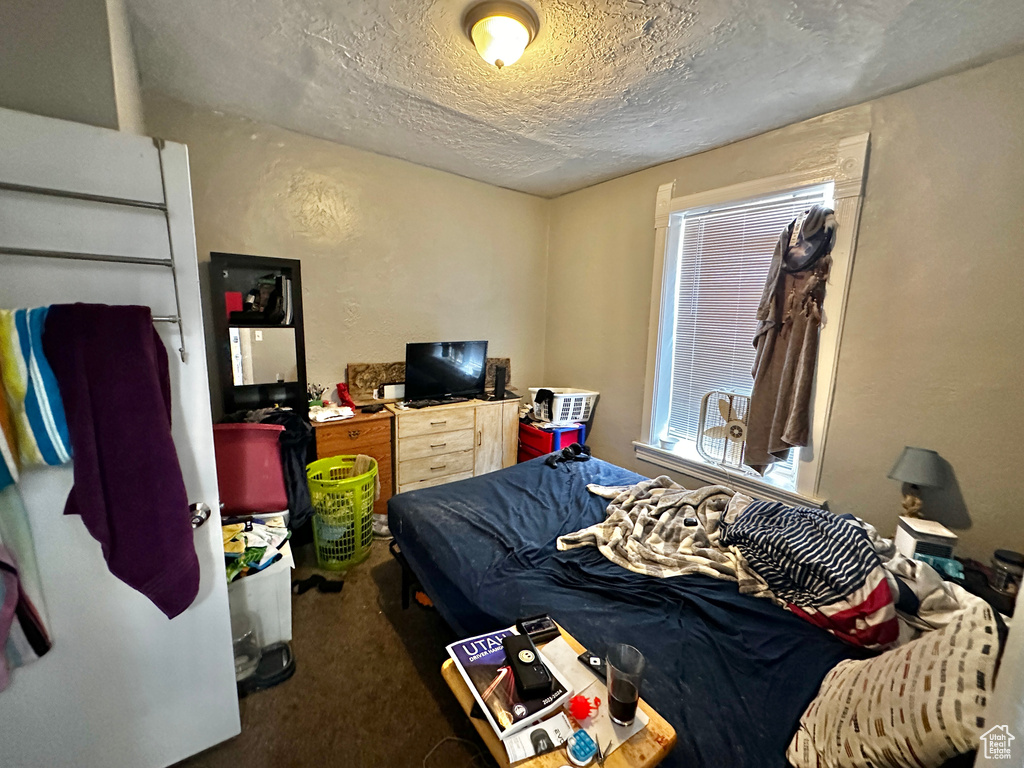 Bedroom featuring a textured ceiling and dark colored carpet