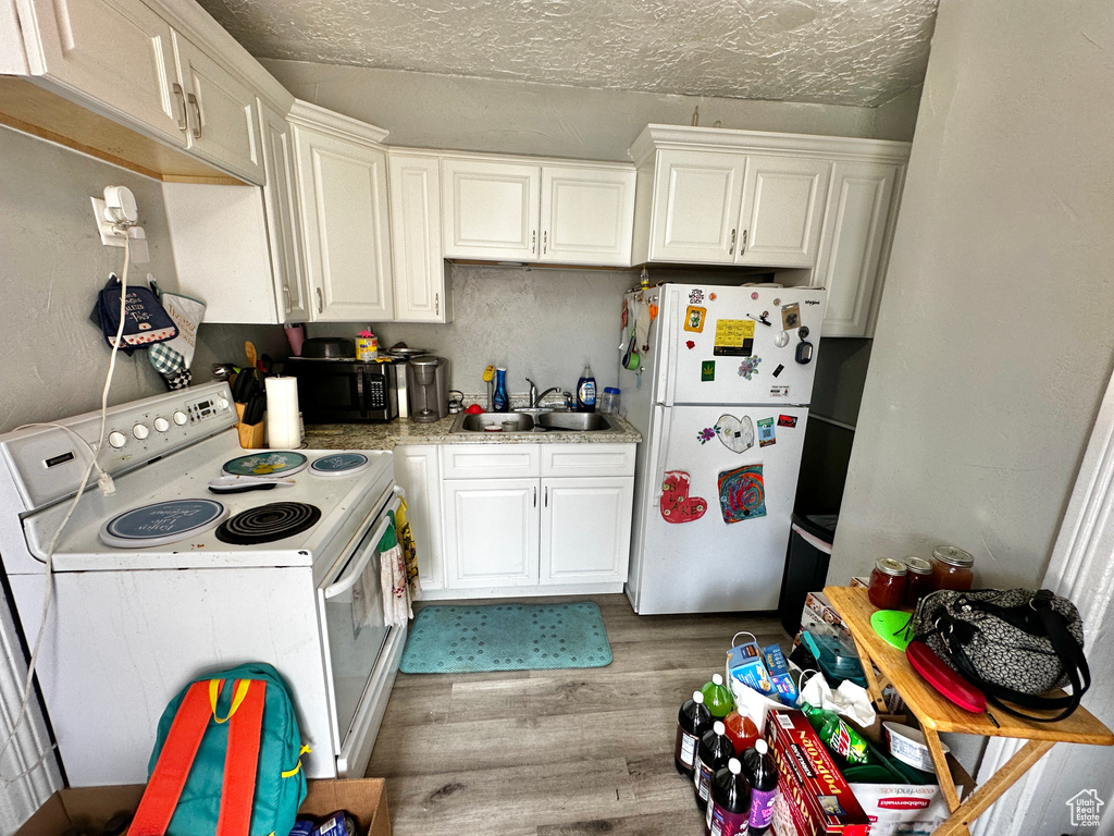 Kitchen featuring white cabinets, sink, light hardwood / wood-style floors, and white appliances