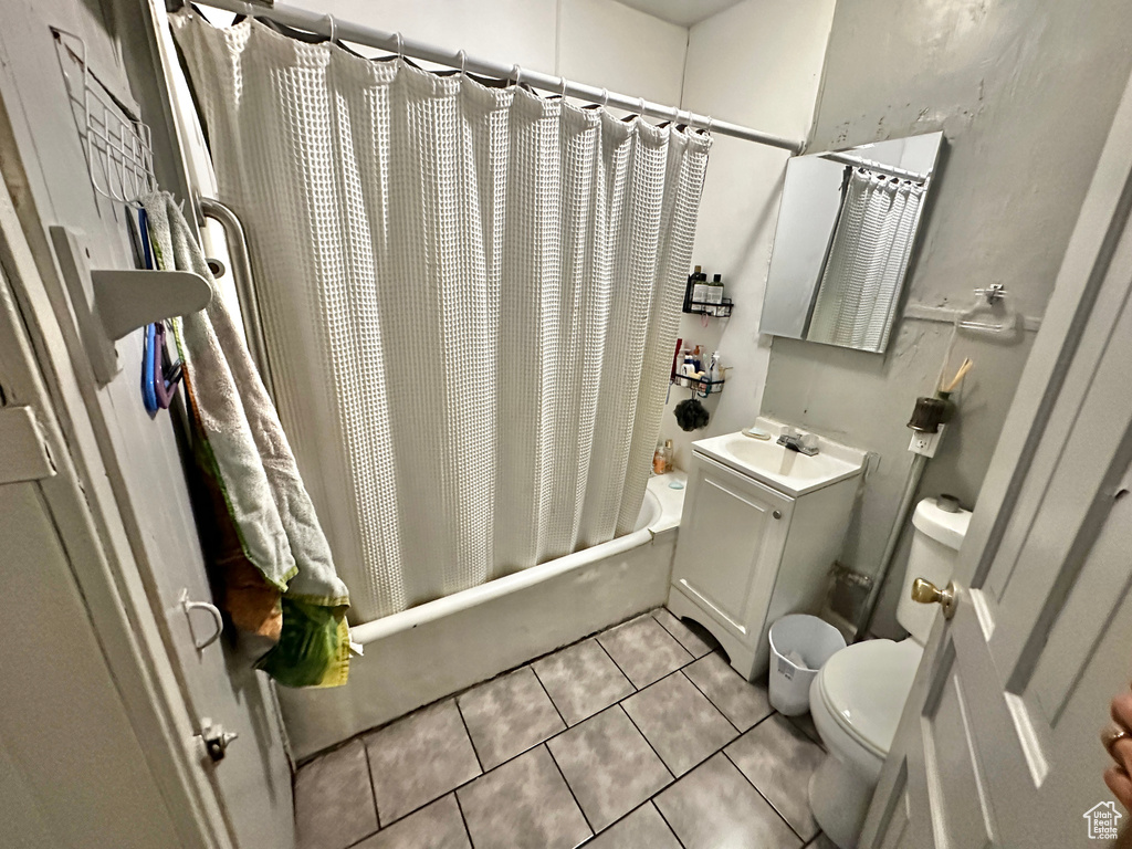 Full bathroom with vanity, shower / bath combo with shower curtain, toilet, and tile patterned floors