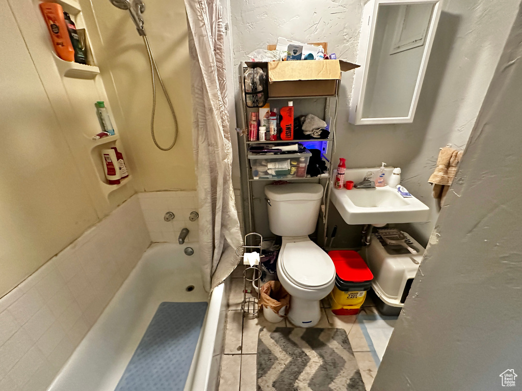 Full bathroom with tile patterned floors, sink, shower / tub combo, and toilet