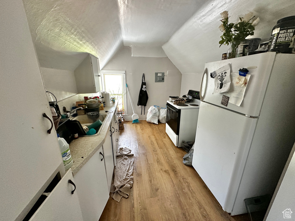 Kitchen with light wood-type flooring, sink, lofted ceiling, white cabinetry, and white appliances