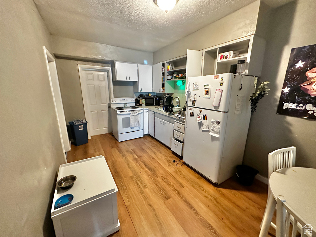 Kitchen featuring white cabinets, white appliances, a textured ceiling, light wood-type flooring, and sink