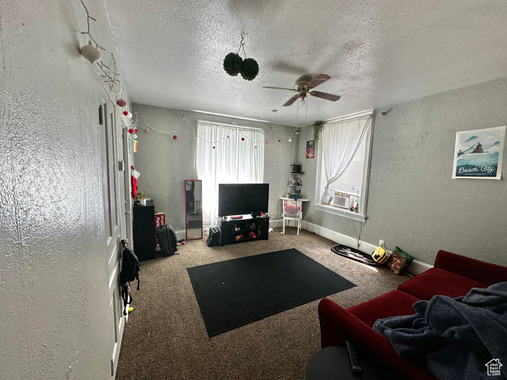 Living room featuring a textured ceiling, ceiling fan, and carpet floors