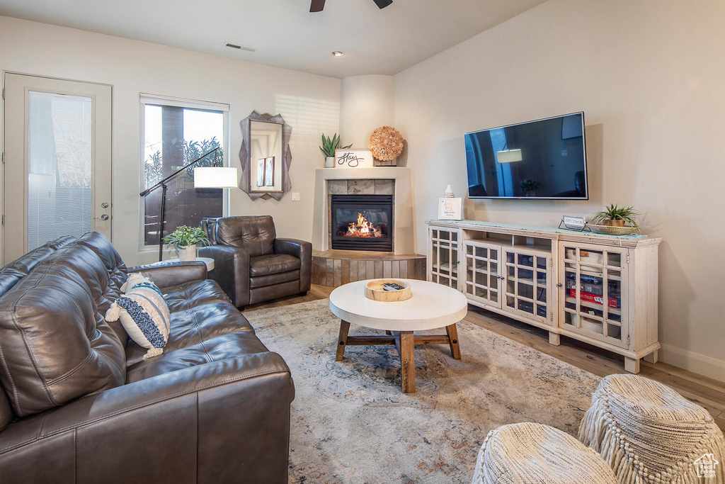 Living room with hardwood / wood-style flooring, a tile fireplace, and ceiling fan