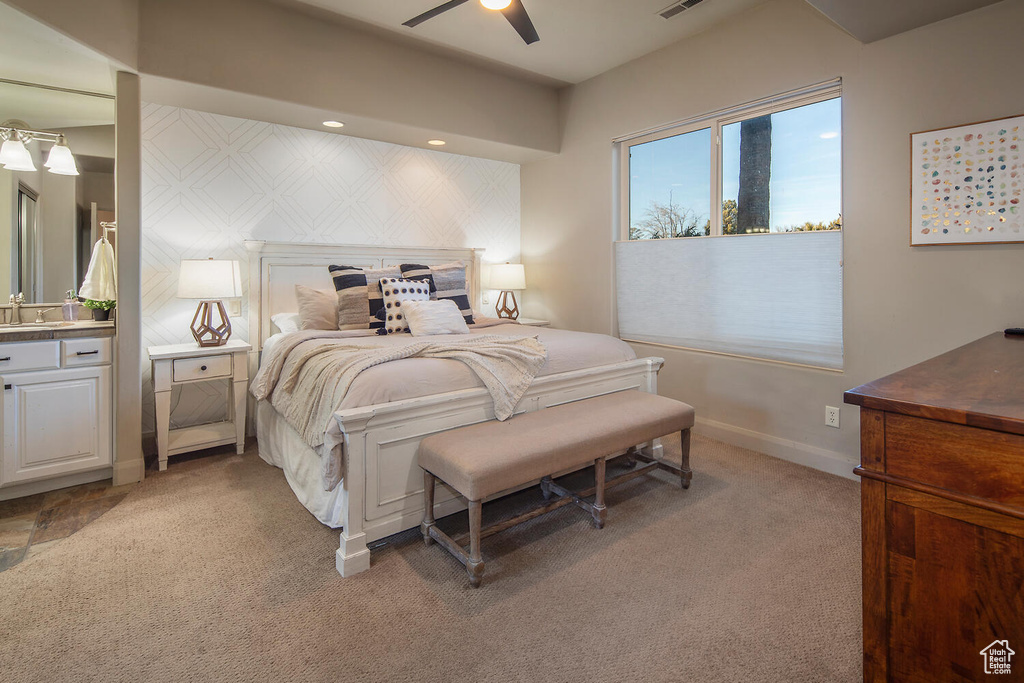 Bedroom with light colored carpet, sink, and ceiling fan