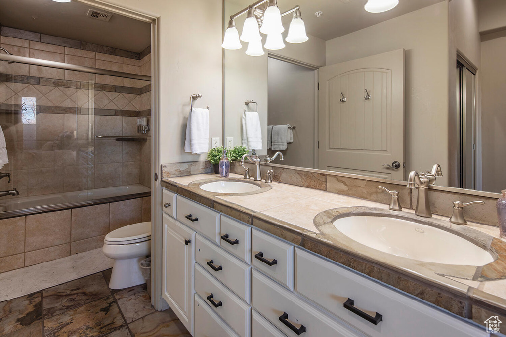 Bathroom with tile patterned flooring, double sink vanity, and toilet