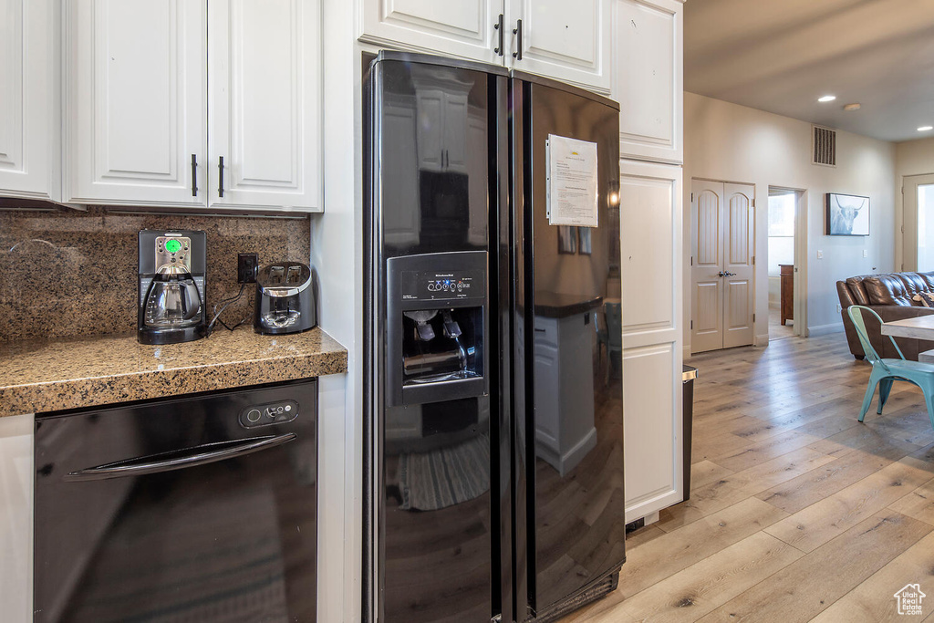 Kitchen featuring white cabinets, black appliances, light hardwood / wood-style flooring, and decorative backsplash