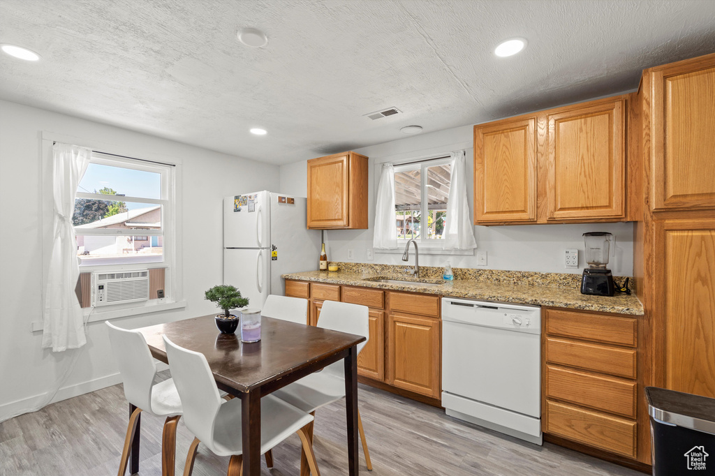 Kitchen with light stone countertops, light hardwood / wood-style flooring, white appliances, and sink