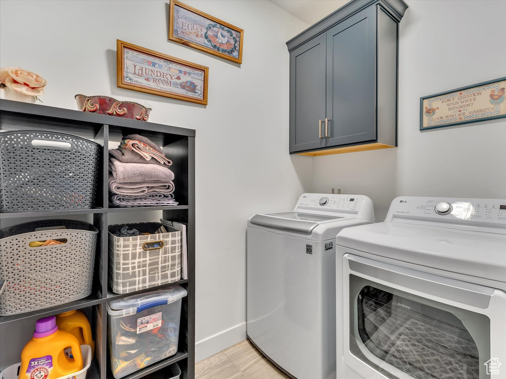 Clothes washing area featuring light hardwood / wood-style floors, separate washer and dryer, and cabinets