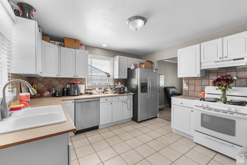 Kitchen featuring decorative backsplash, light tile patterned floors, appliances with stainless steel finishes, and sink