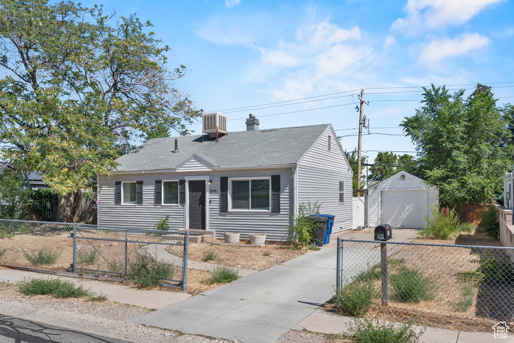 View of front of home with a garage and an outbuilding