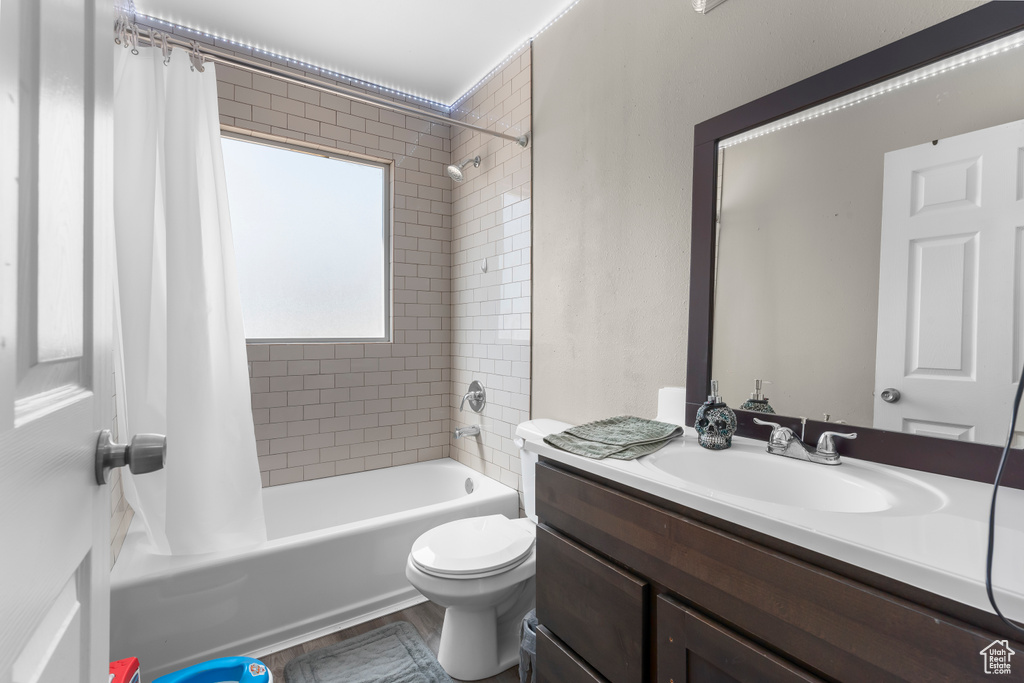 Full bathroom with vanity, shower / bath combo with shower curtain, and toilet