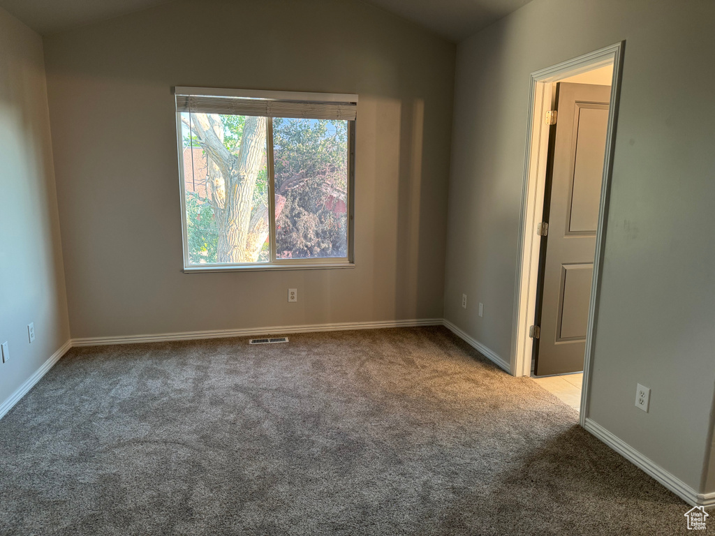 Unfurnished room with carpet flooring and vaulted ceiling