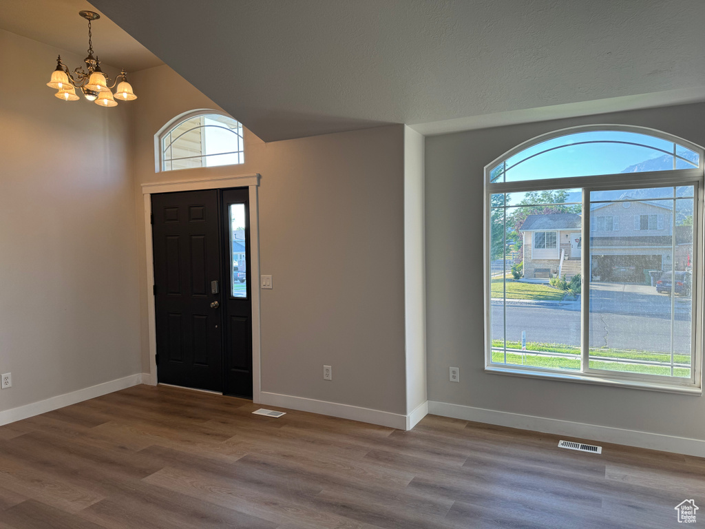 Foyer with plenty of natural light, a chandelier, and wood-type flooring