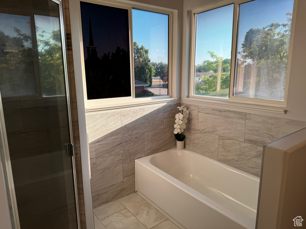 Bathroom featuring separate shower and tub, tile patterned flooring, and tile walls