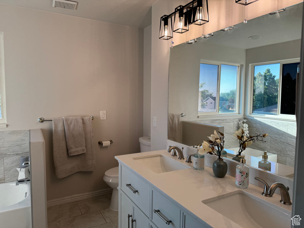 Bathroom featuring dual vanity, tile patterned flooring, a bath, and toilet