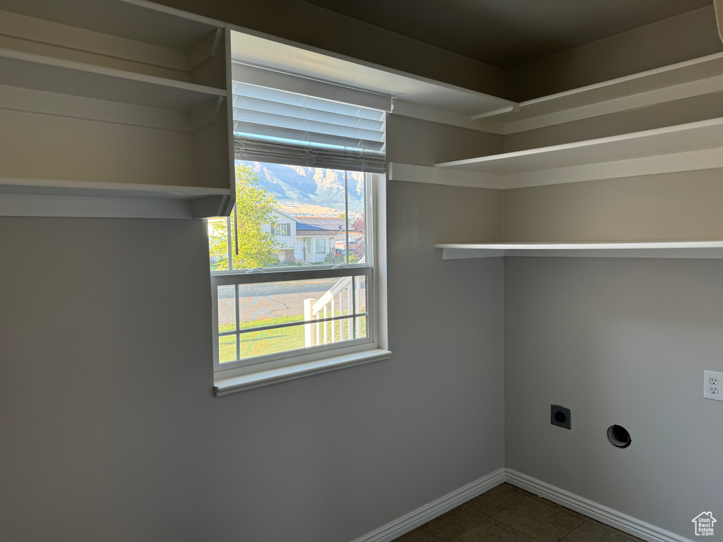 Laundry room with dark tile patterned floors and hookup for an electric dryer