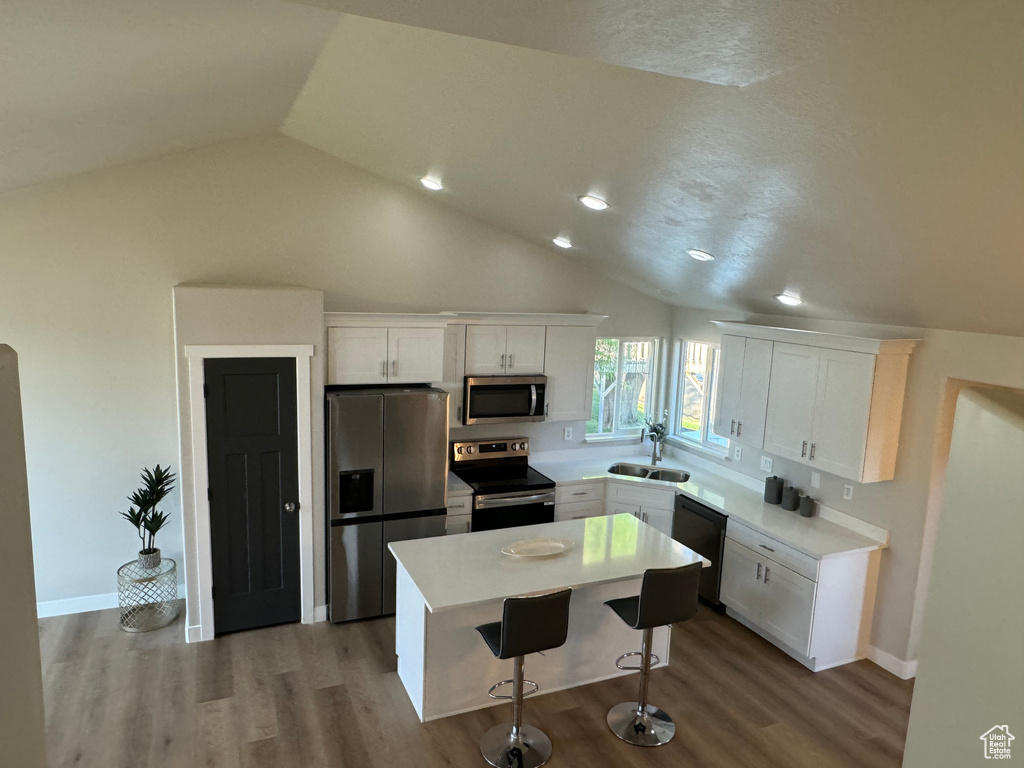 Kitchen with lofted ceiling, appliances with stainless steel finishes, and wood-type flooring